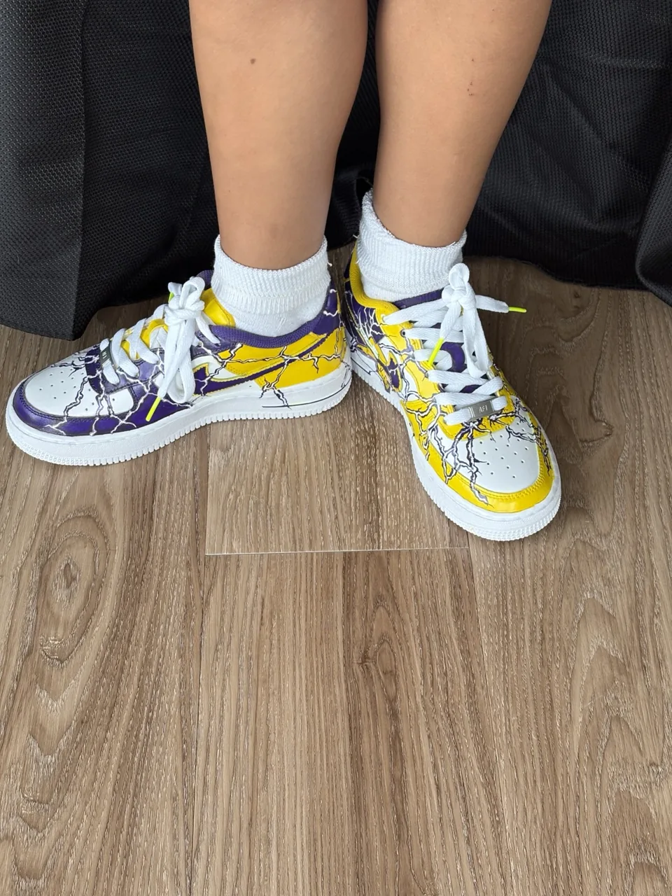 Completed purple and gold kids’ custom Air Force 1 sneakers worn on foot